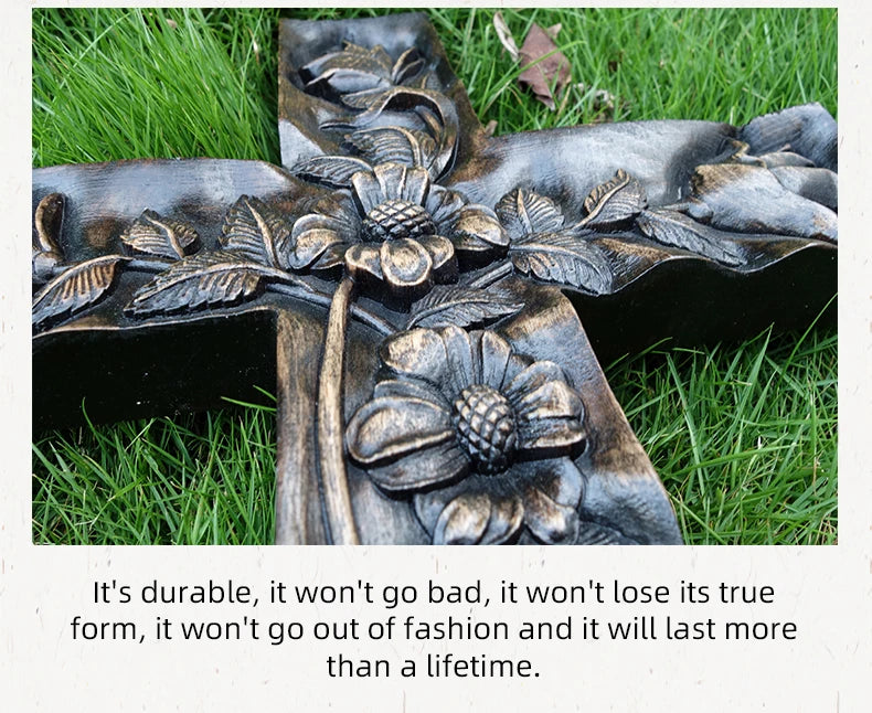 Close-up of the dark, carved wooden cross with floral relief lying on bright green grass. The caption below highlights the product's durability, stating: "It's durable, it won't go bad, it won't lose its true form, it won't go out of fashion and it will last more than a lifetime.