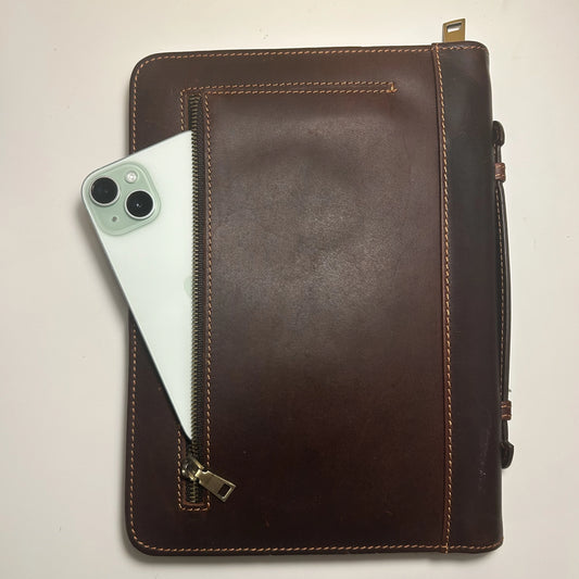 Genuine leather Bible cover showing front zipper pocket holding a smartphone, symbolizing practical design.