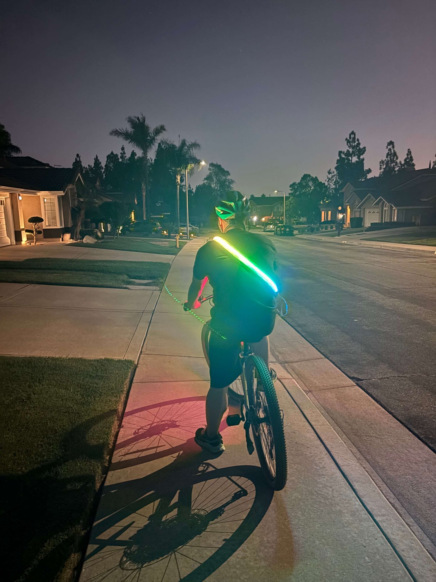 Cyclist wearing an LED safety strip harness on the back for high visibility while riding at night