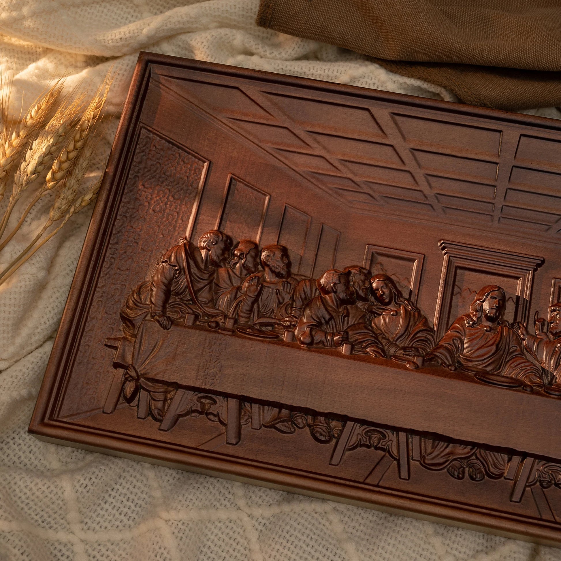 The Last Supper wood carving placed on soft beige fabric, showing intricate details and smooth polished texture