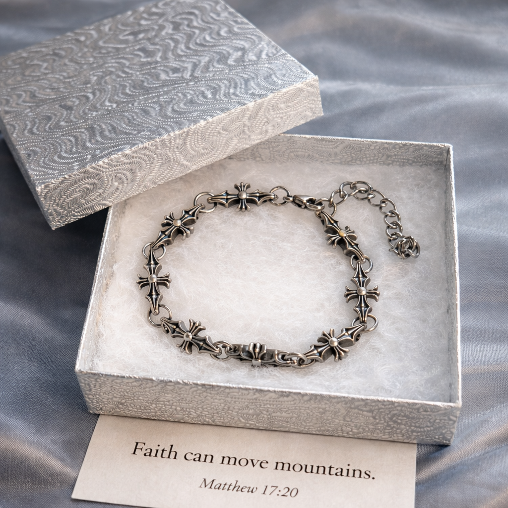 Silver cross bracelet in an open jewelry box with a card on a textured surface