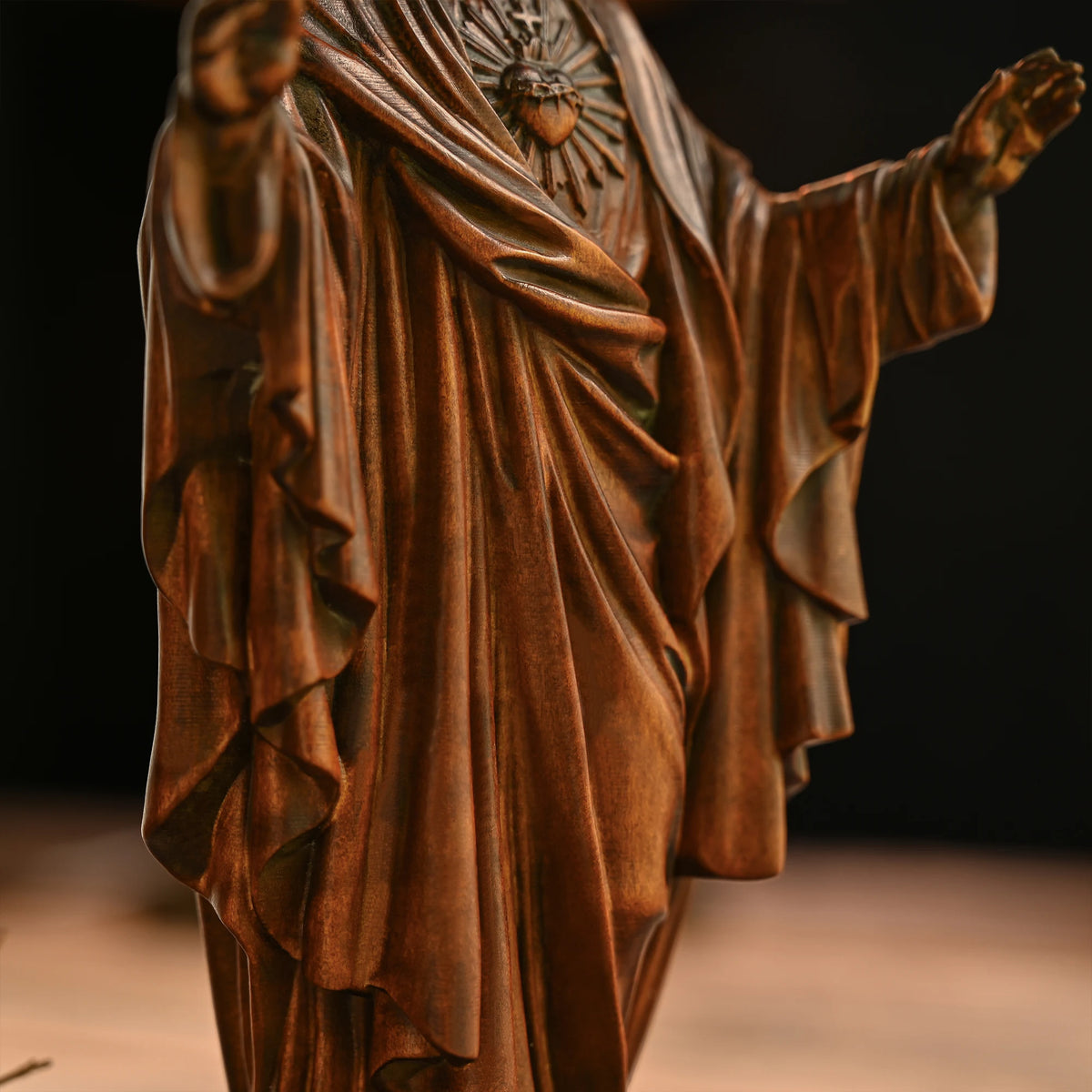 Close-up of a 3D carved beechwood Jesus statue showing detailed robe, hands, and chest carving