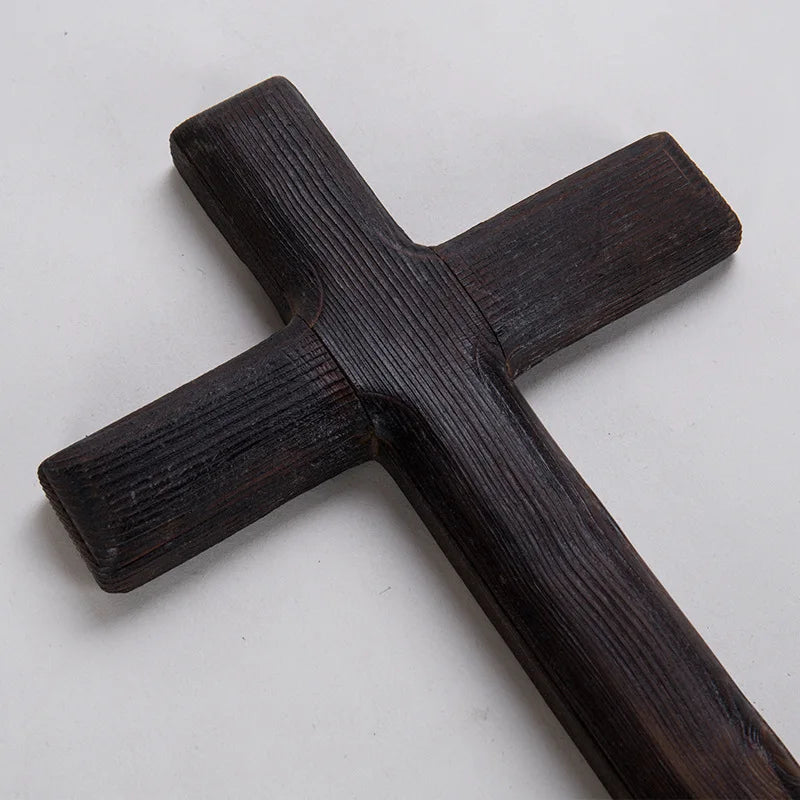 A close-up detail shot of the dark wooden cross, emphasizing the clear, rough texture of the wood grain and its deep color.