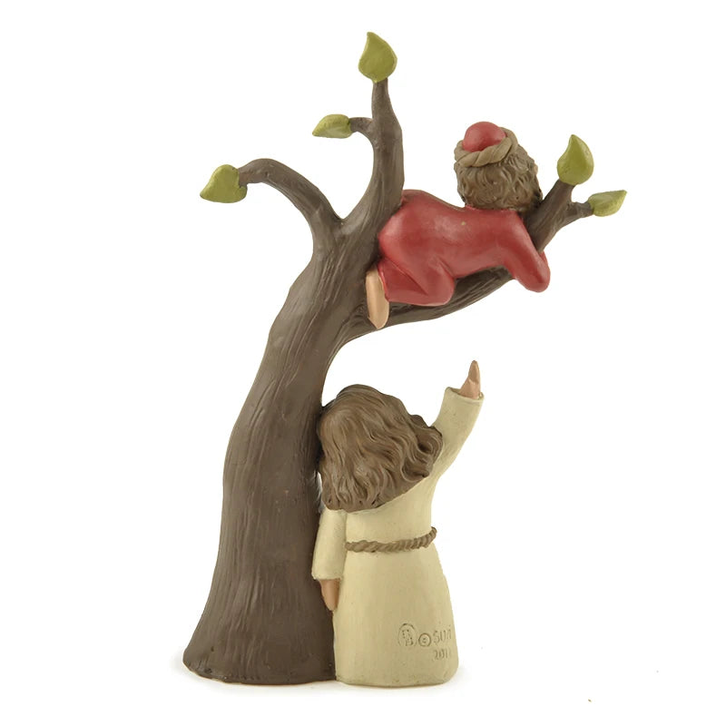 Rear view of the resin sculpture of Zacchaeus in the sycamore tree, showing the standing figure (Jesus) pointing upward towards Zacchaeus with his back facing the viewer.
