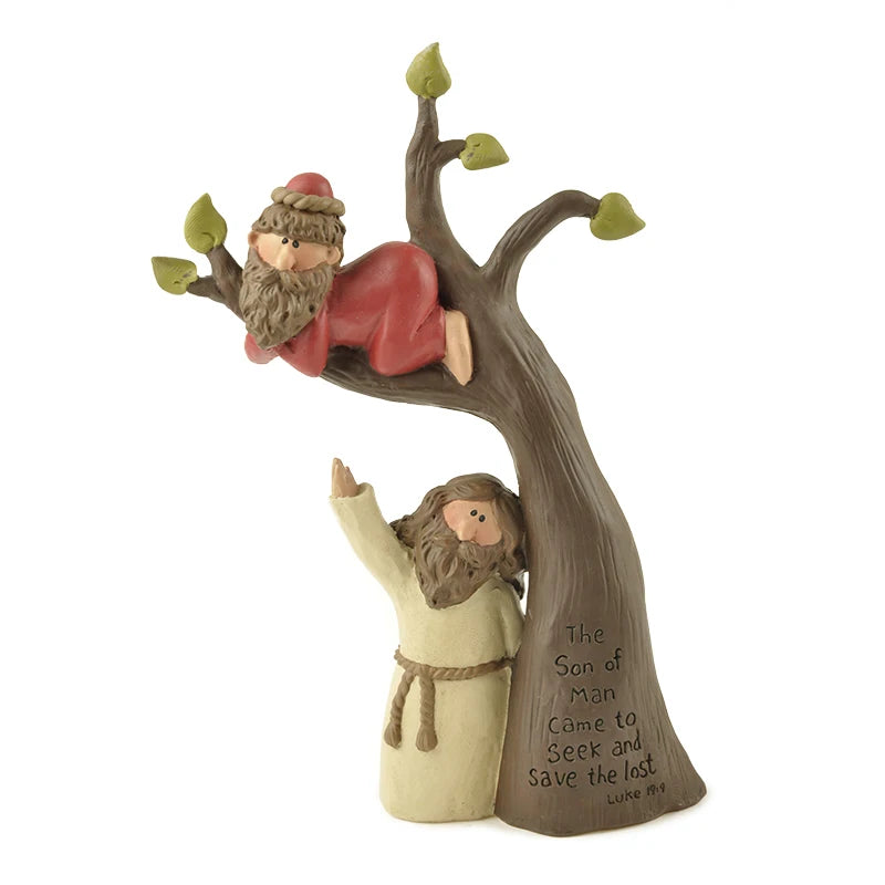 A resin sculpture depicting the Bible story of Zacchaeus climbing a sycamore tree, with a standing figure below reaching up, and the scripture "The Son of Man Came to Seek and Save the lost. Luke 19:10" engraved on the tree trunk.