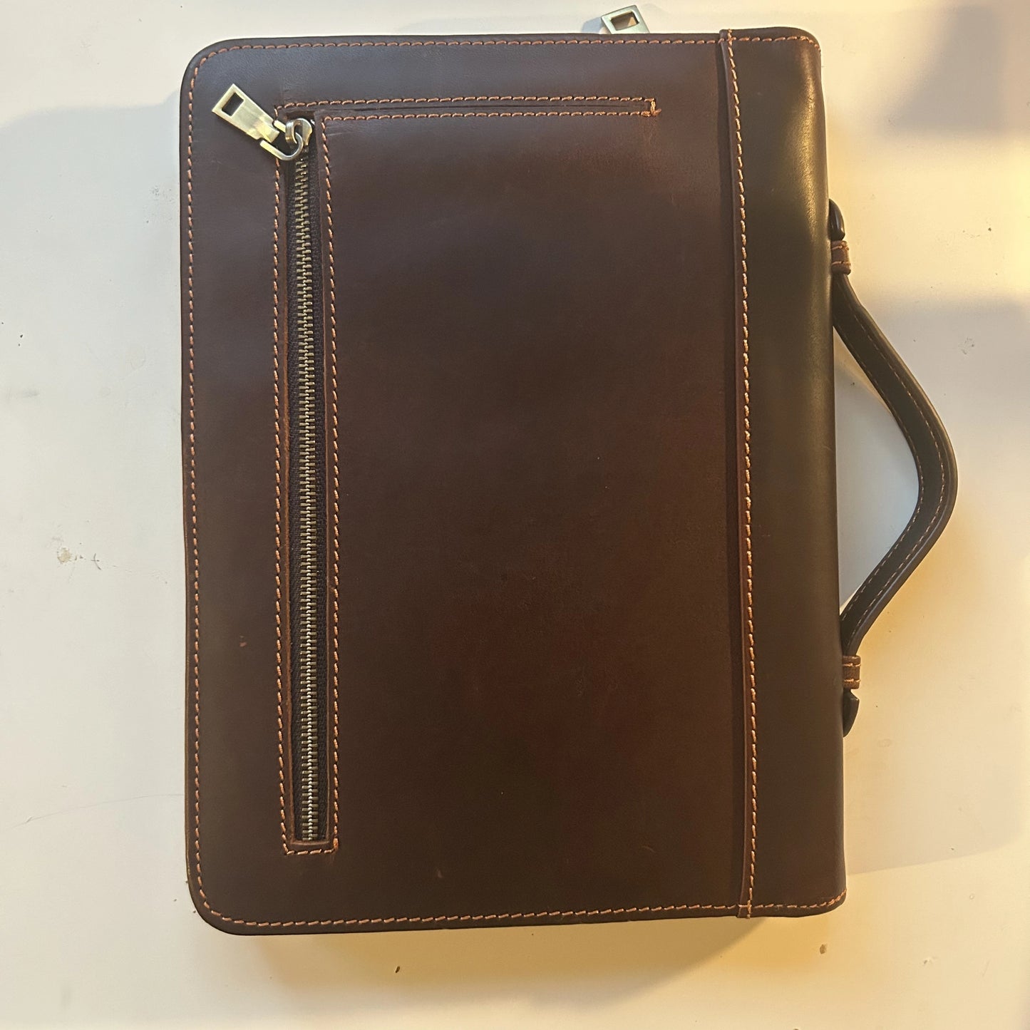 Full back view of the brown leather Bible cover showing the handle and zipper closure.