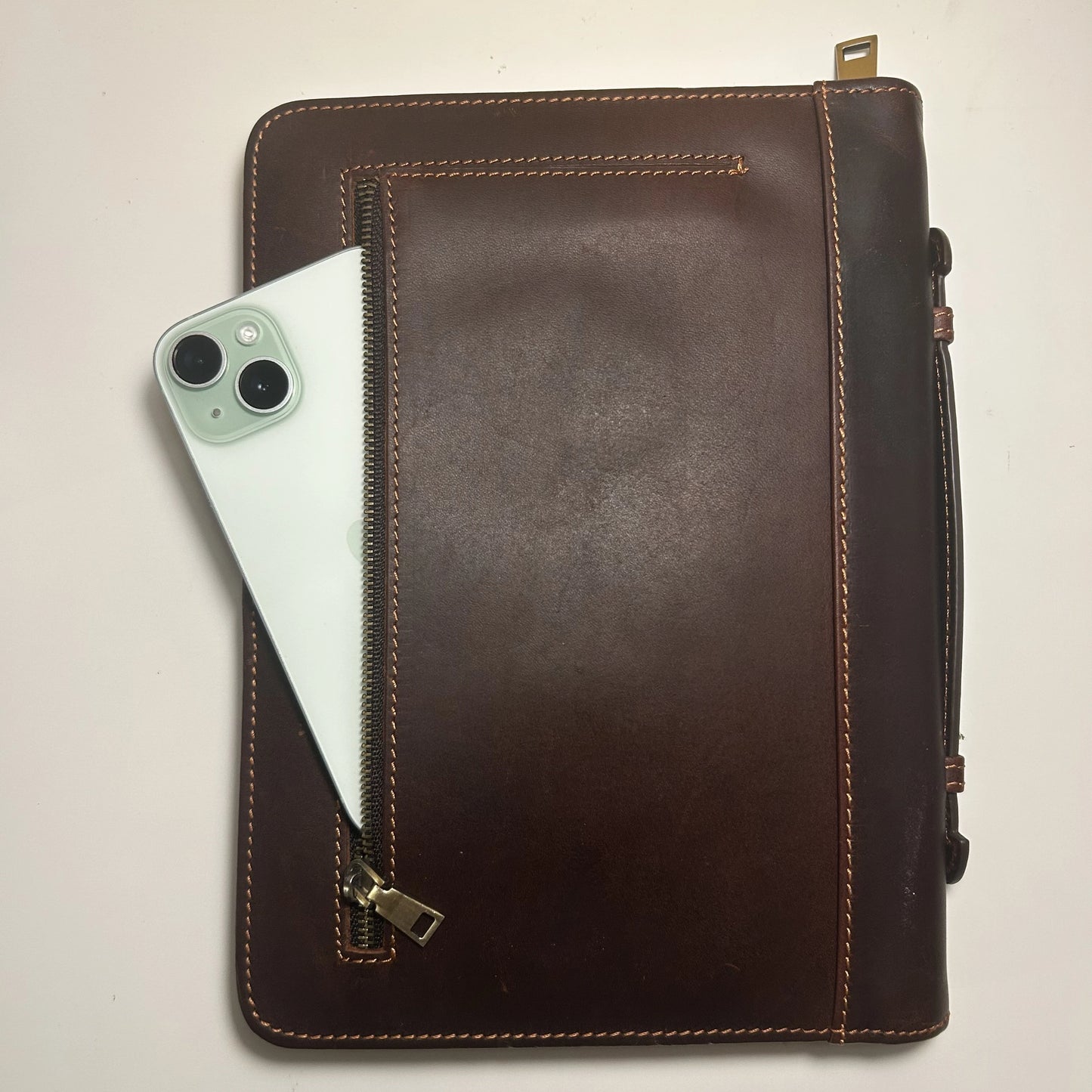 Genuine leather Bible cover showing front zipper pocket holding a smartphone, symbolizing practical design.