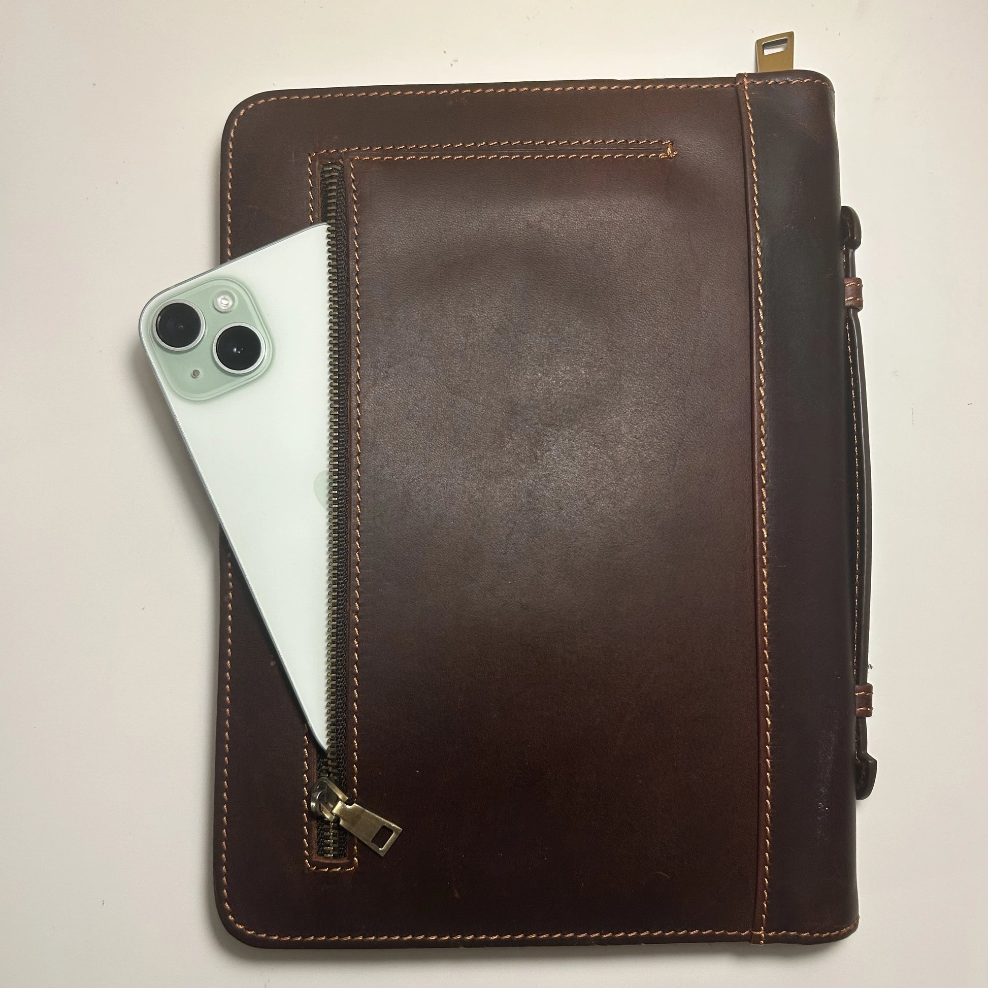 Genuine leather Bible cover showing front zipper pocket holding a smartphone, symbolizing practical design.