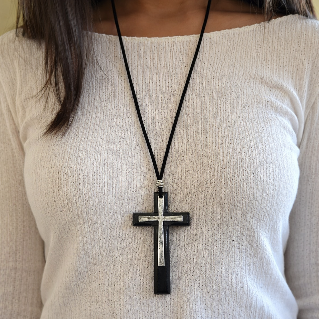 Woman wearing black wood cross necklace with silver metal inlay
