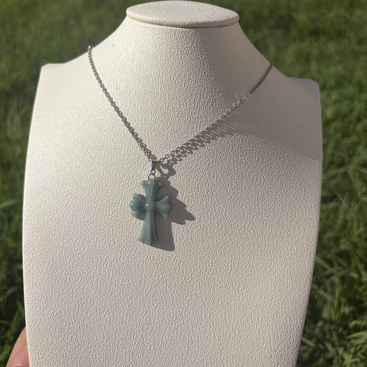 Blue water jadeite cross pendant displayed on a necklace