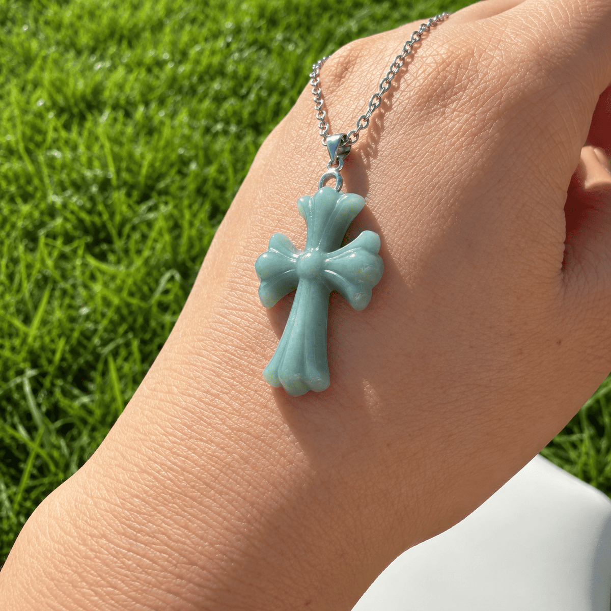 Close-up of a natural blue water jadeite cross pendant in natural light