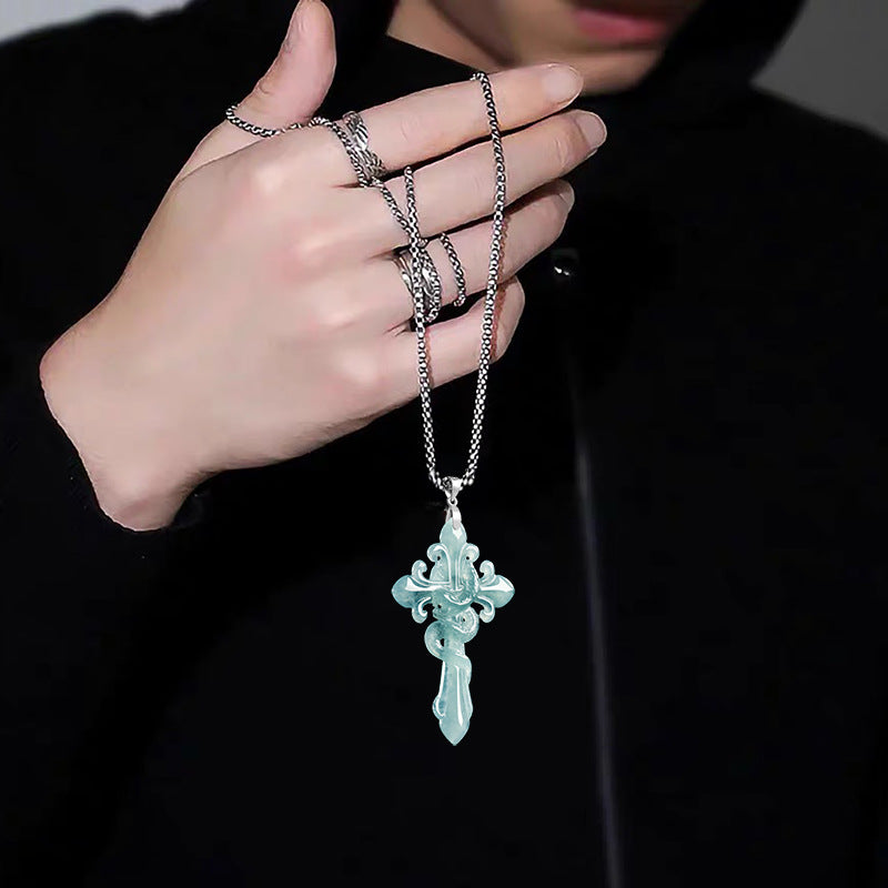 Hand wearing multiple rings with a jadeite serpent cross pendant necklace against a dark background