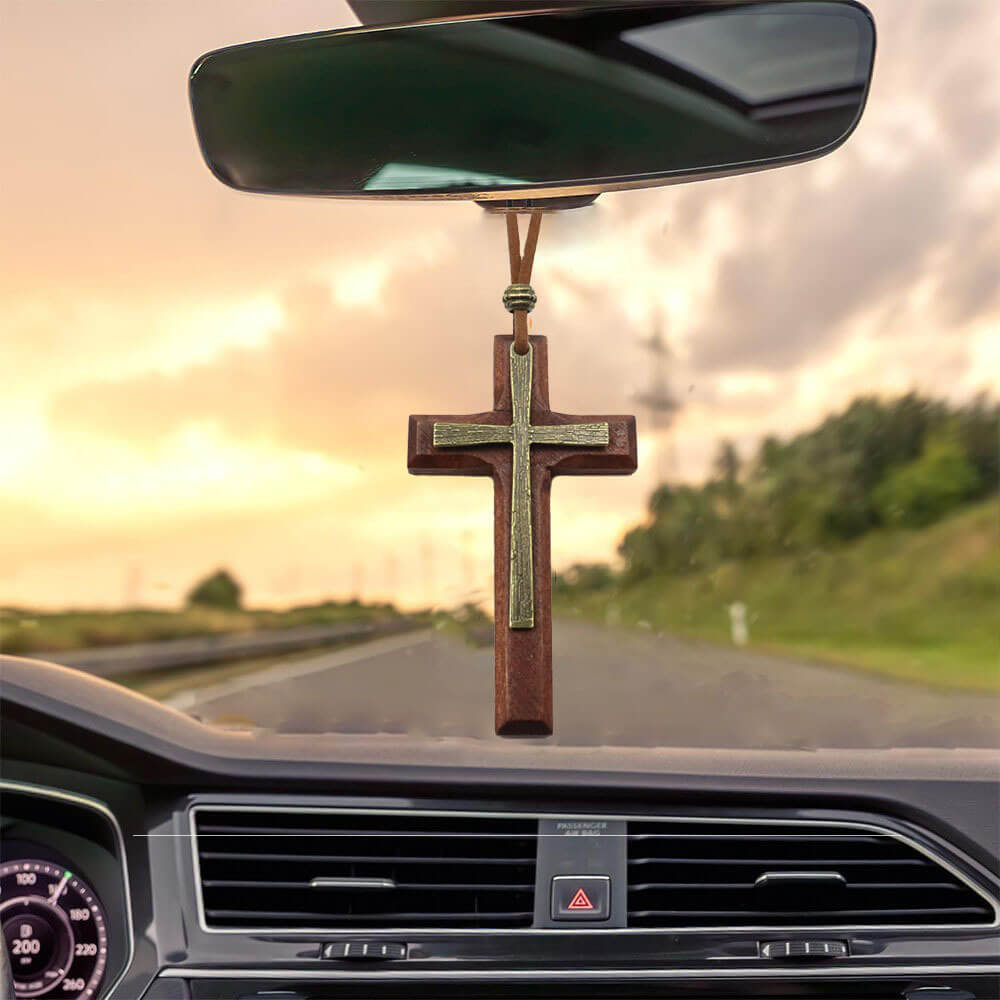Brown wood cross necklace with brass metal overlay hanging inside car