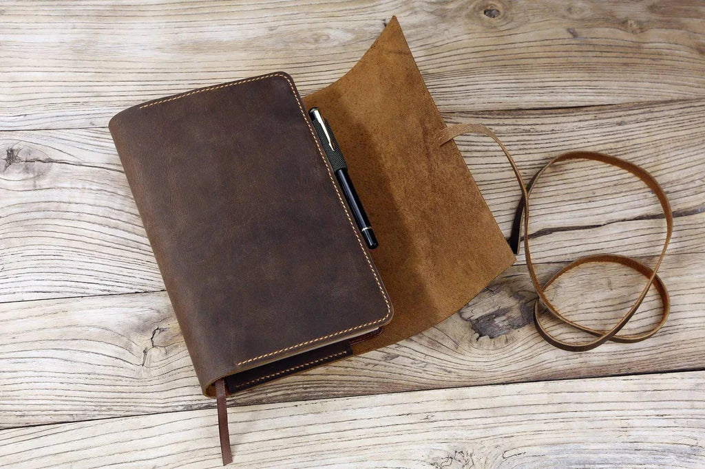 Leather Bible cover with strap partially open, revealing brown suede inner surface