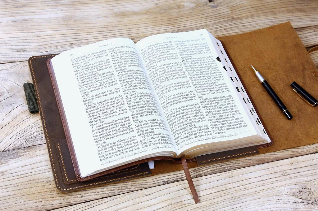 Open Bible displayed inside brown leather cover, with pen placed nearby