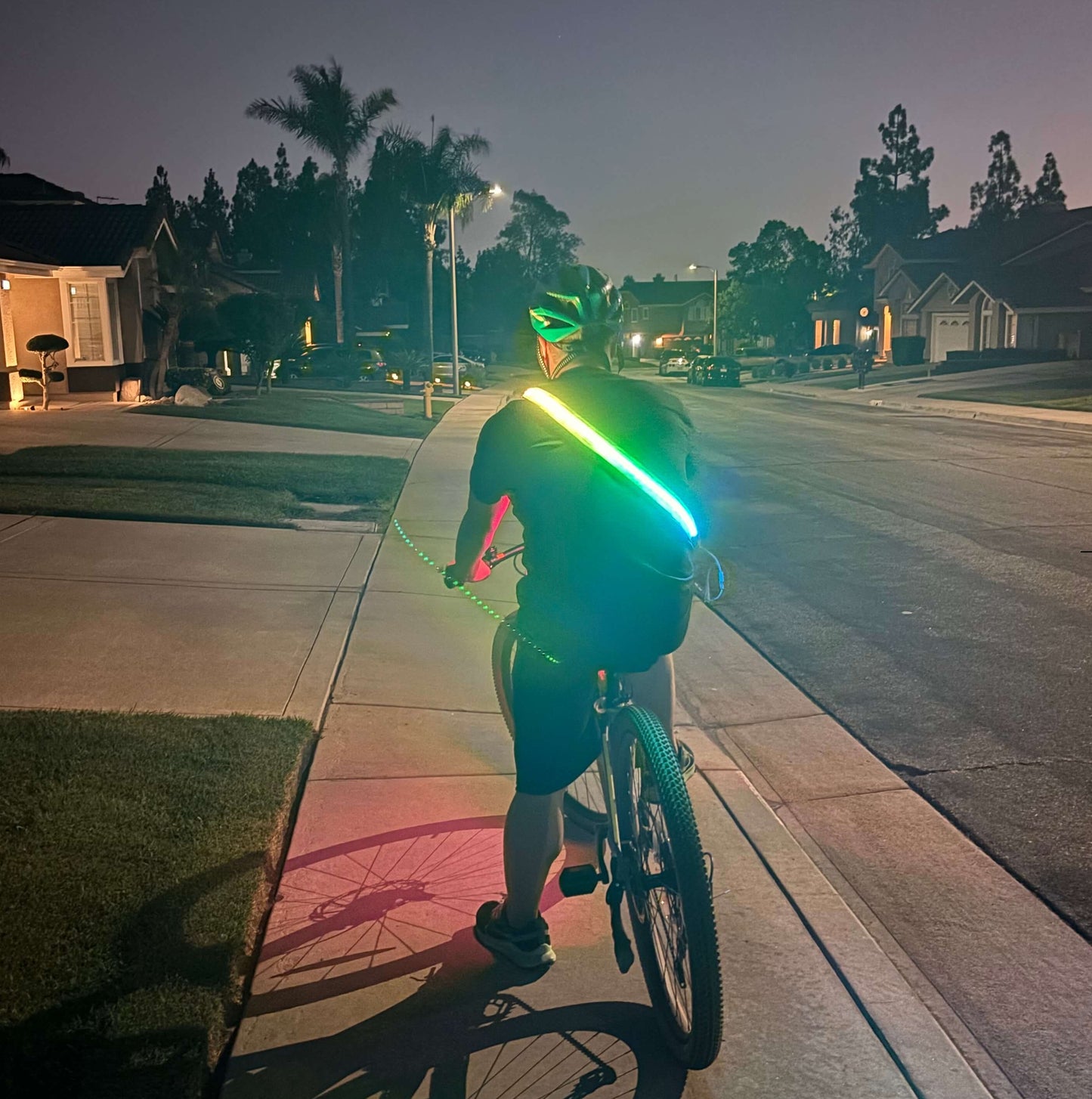 Cyclist wearing an LED safety strip on a backpack for high visibility during night riding