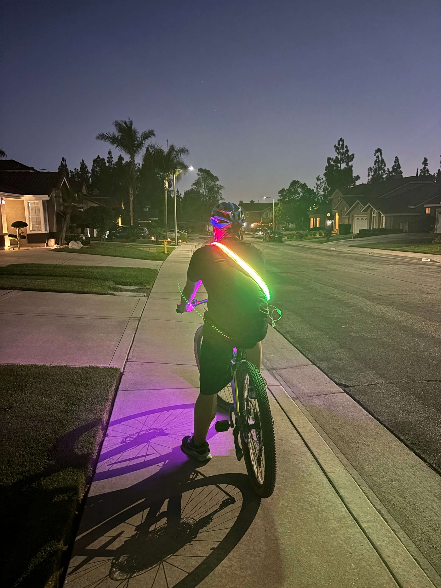 Cyclist wearing an LED safety strip harness for high visibility while riding a bike at night