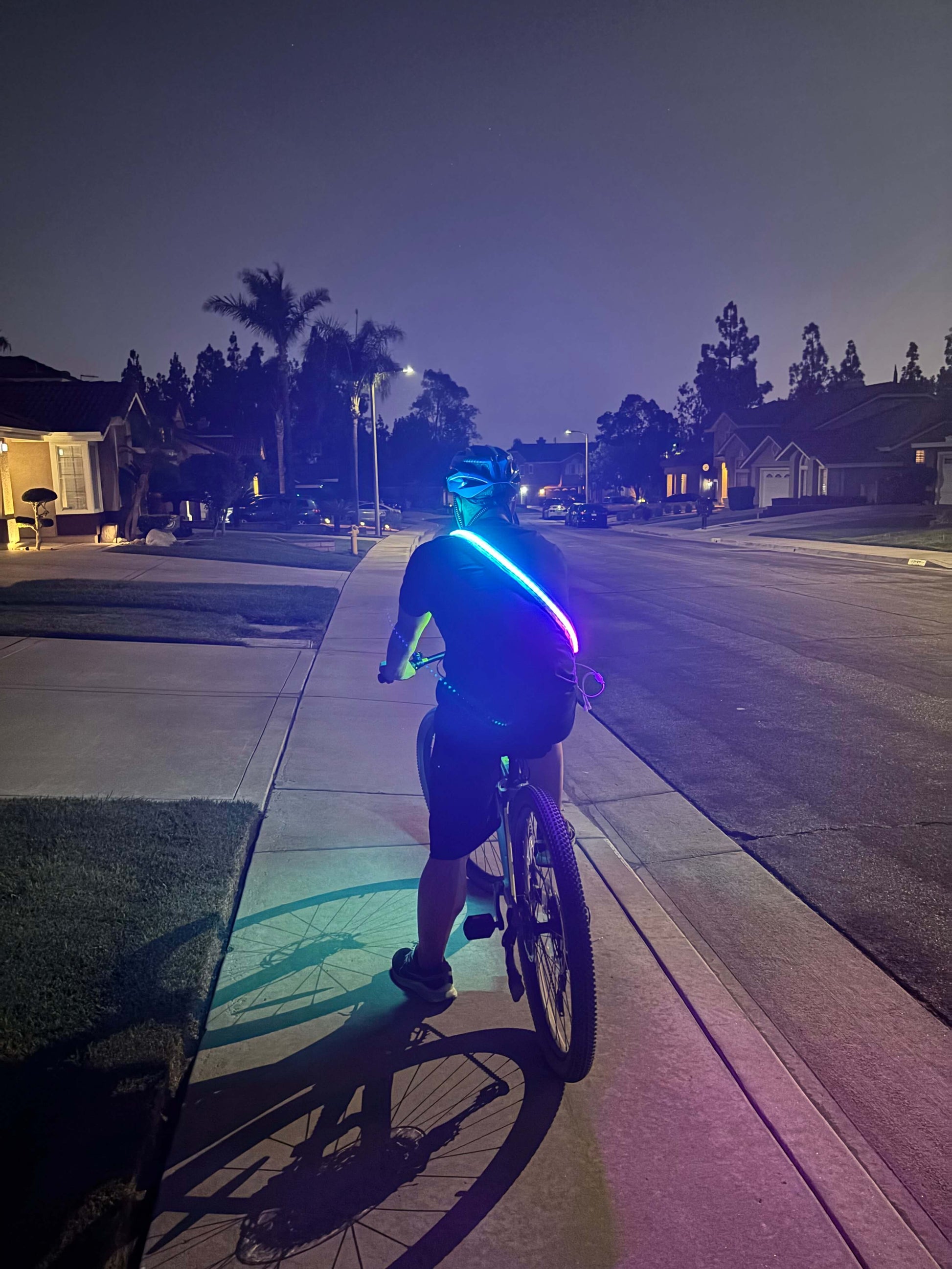Cyclist wearing an LED safety strip harness for increased visibility while riding at night