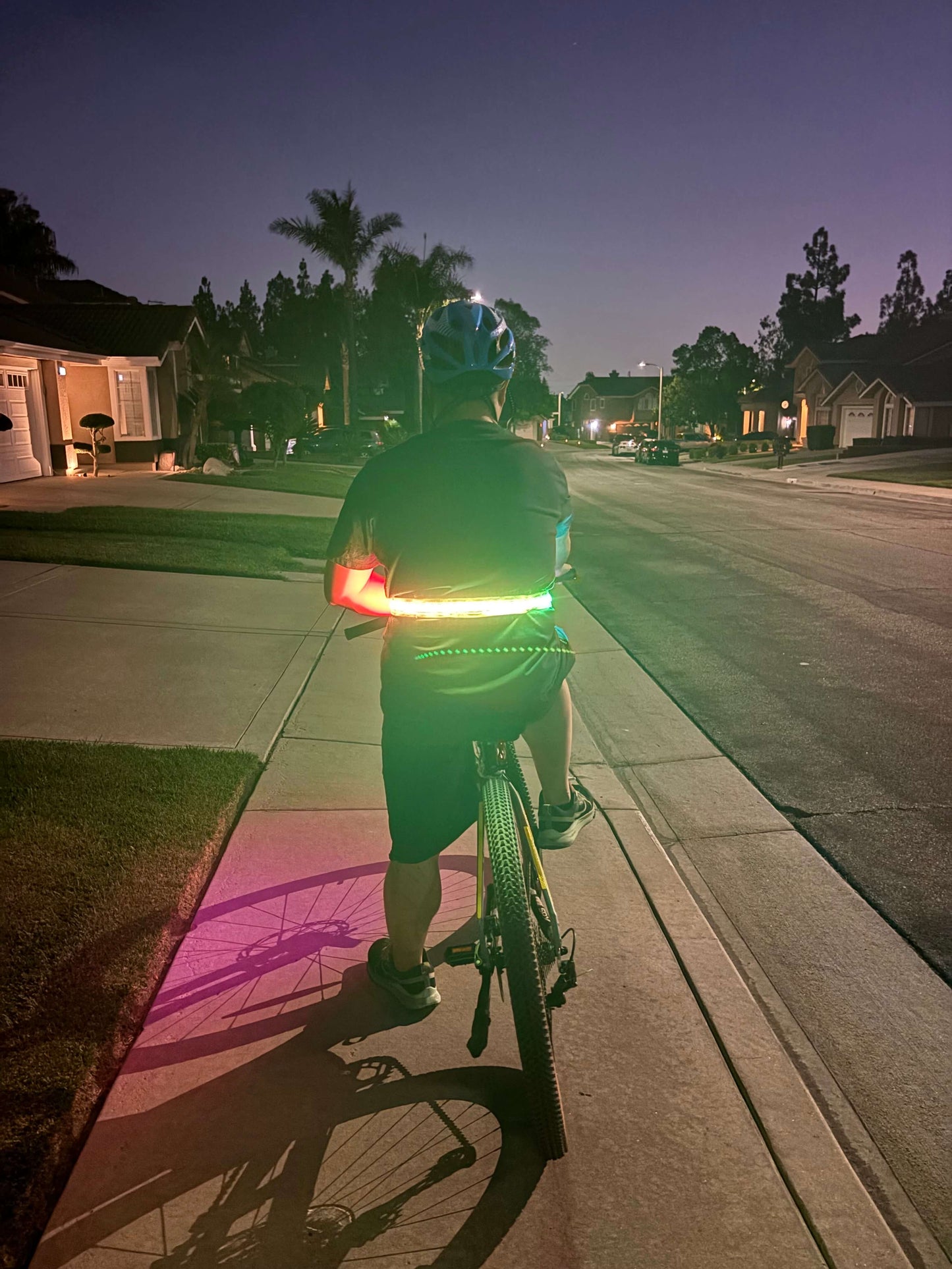 Cyclist wearing an LED safety strip around the waist for high visibility while riding at night