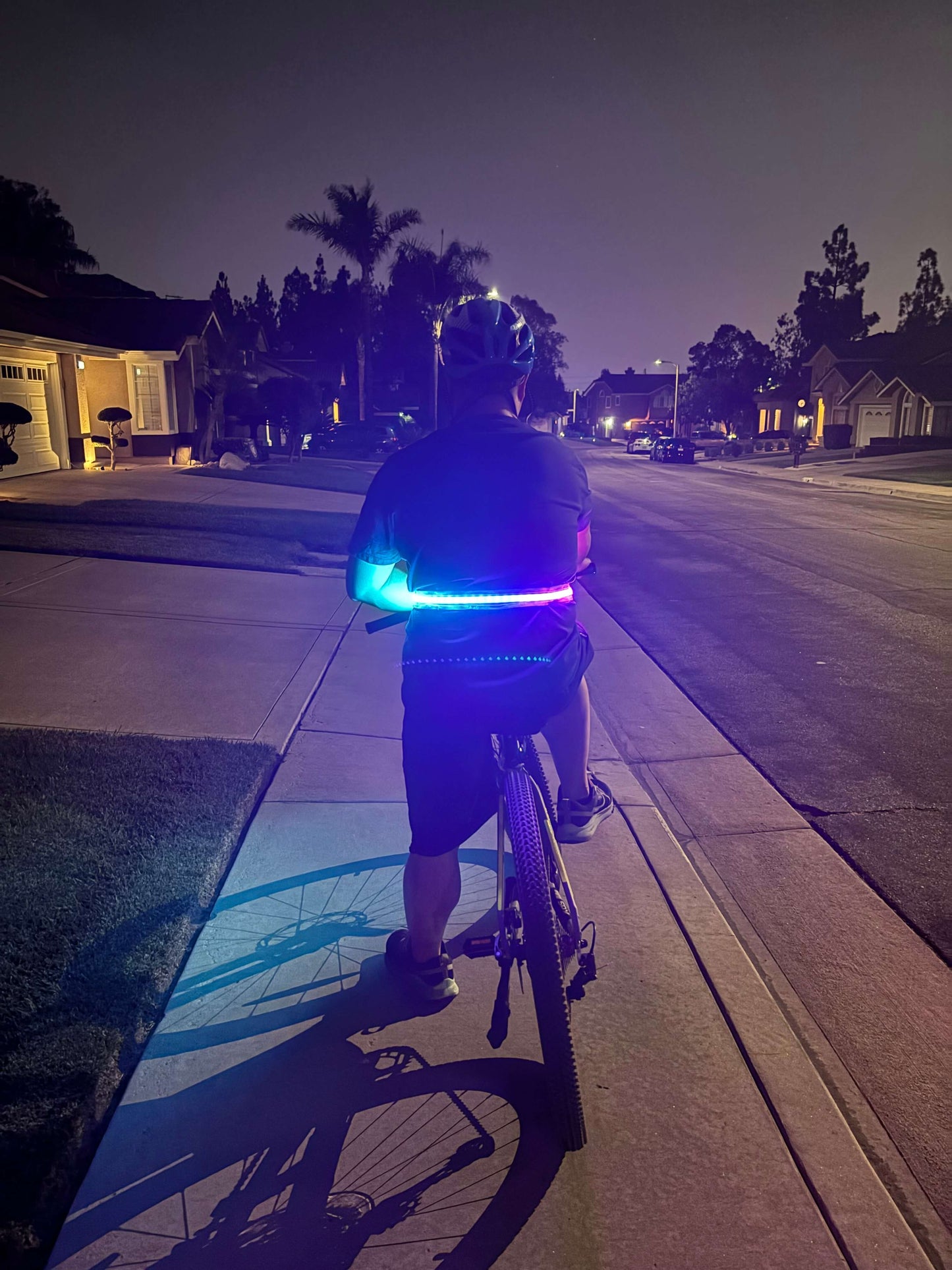 Cyclist wearing an LED safety strip mounted around the waist for high visibility while riding at night