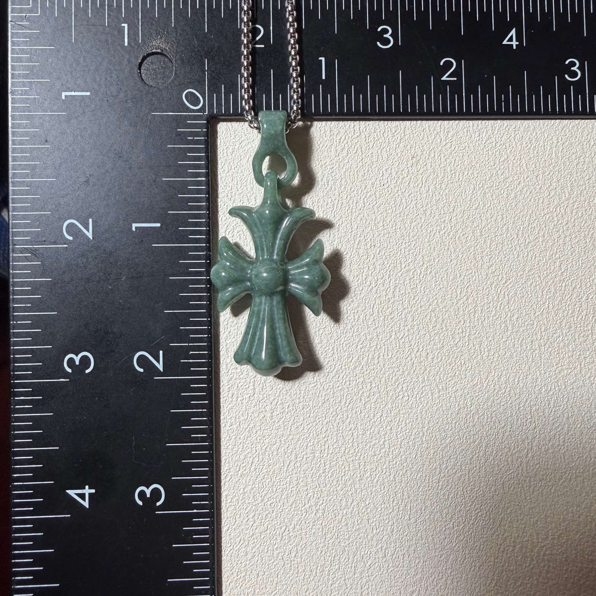 Natural Grade A jadeite cross pendant shown next to a ruler for size reference