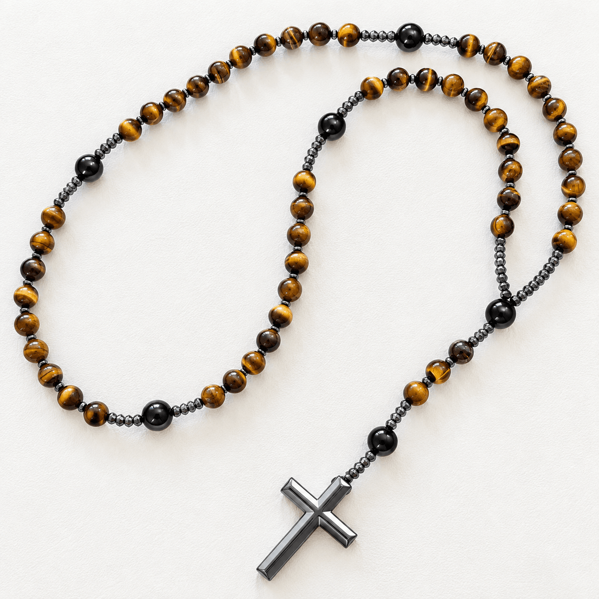 A beaded rosary necklace featuring round brown and black tiger's eye beads, separated by small dark metallic beads, with a dark metallic cross pendant, displayed on a clean white background.