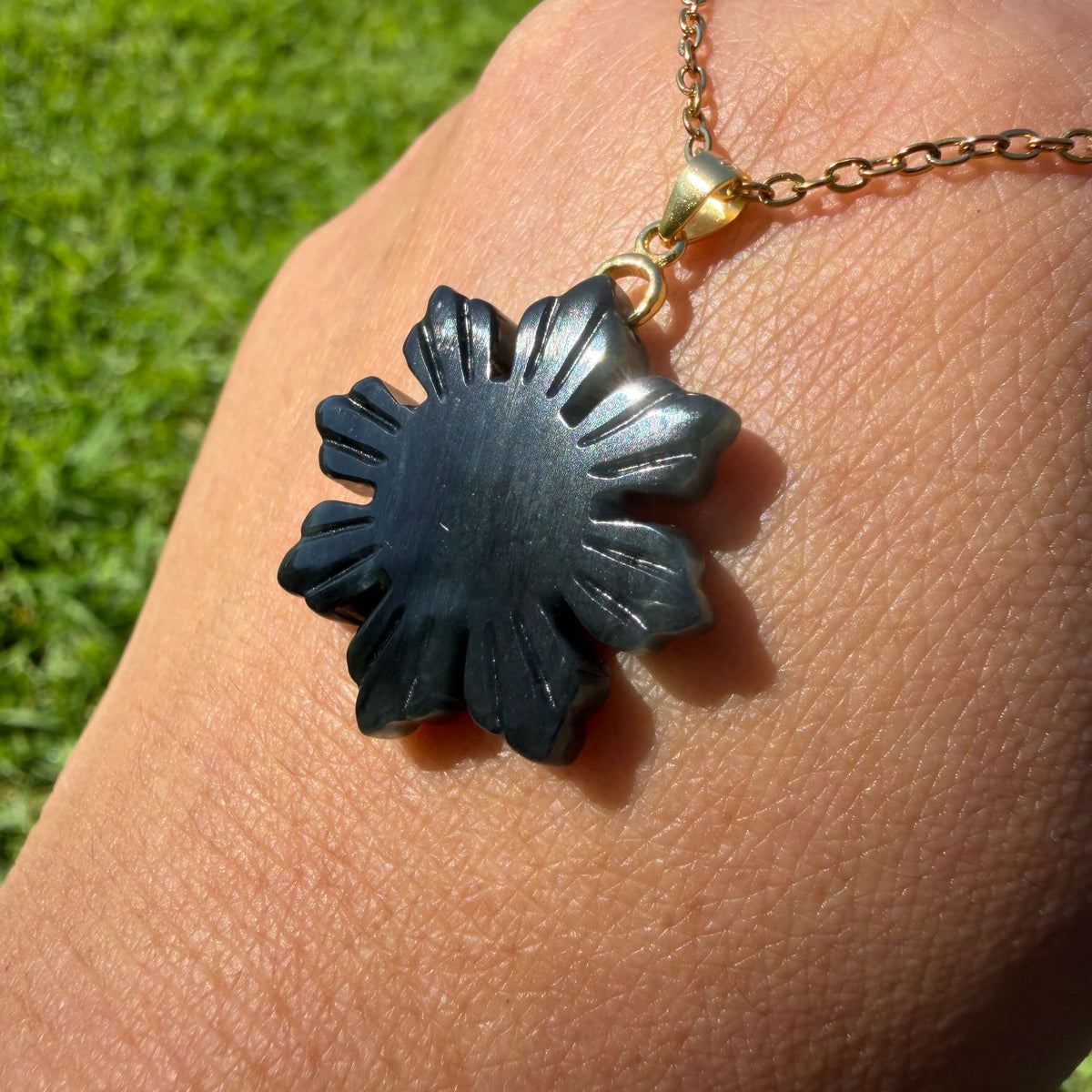 Natural untreated Wuji jadeite Filipino Sunflower pendant held in hand to show its carved design