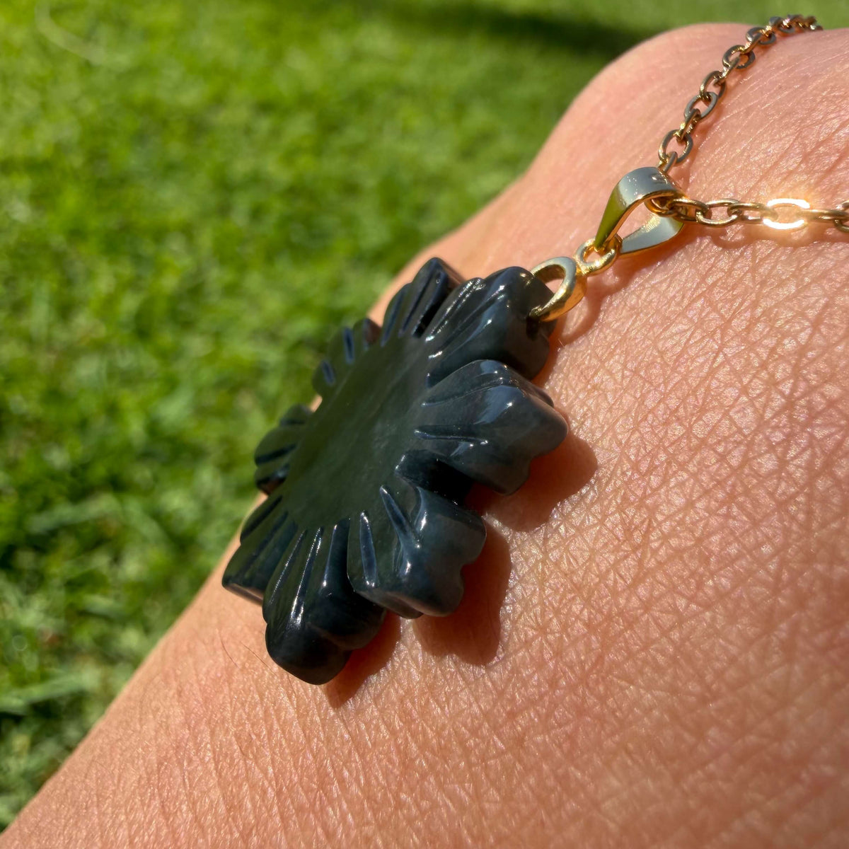 Side view of a natural untreated Wuji jadeite Filipino Sunflower pendant showing its carved depth and polished edges
