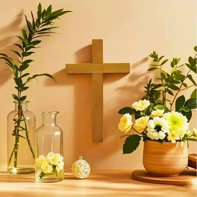 Solid cherry wood wall cross displayed on a warm-toned wall with flowers and glass vases for home decor