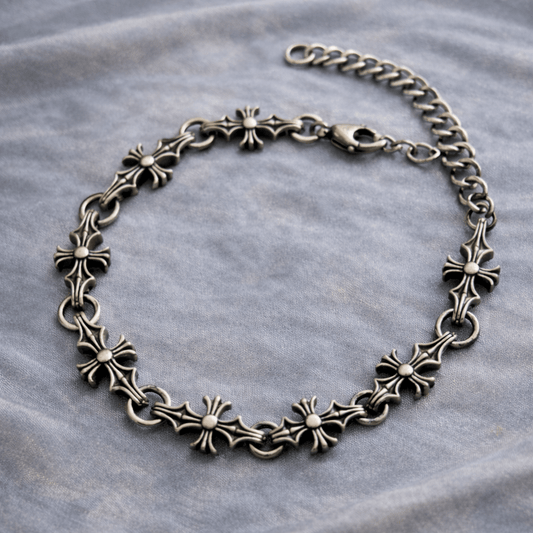 Silver chain bracelet with intricate designs on a gray fabric background